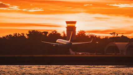 Jet Airplane Landing at Dramatic Sunset Near ATC Control Tower