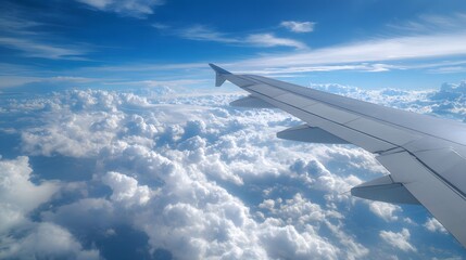 Obraz premium Airplane wing extends over a vast expanse of white cumulus clouds beneath a deep blue sky