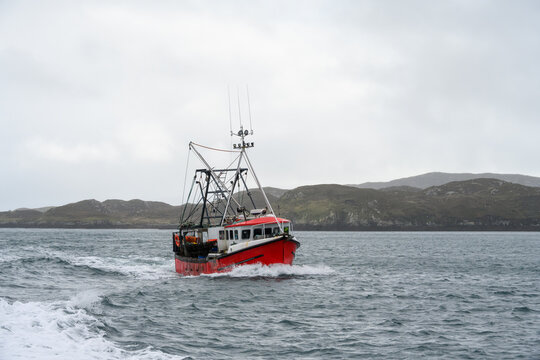Red commercial fishing vessel off the coast of the Isle of Harris, Outer Hebrides, Scotland, UK
