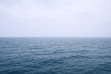Fototapeta premium Calm Blue Ocean Under a Cloudy Sky: Serene Coastal Scene for Travel and Nature Imagery