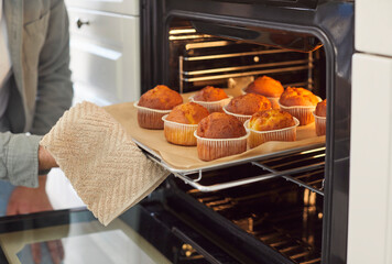 Taking tray with yummy self baked tasty muffins out of oven, enjoy cooking in modern kitchen, house chores, homemade family pastries, culinary hobby, cupcakes dessert, tasty hot fresh bakery