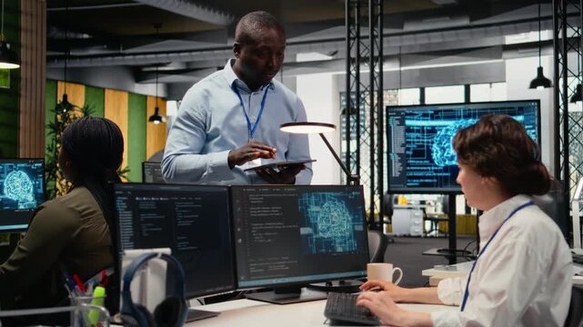 Manager talking with intern in office, using specialized hardware to accelerate complex AI calculations. Team leader teaching trainee how to manage machine learning training datasets, camera A