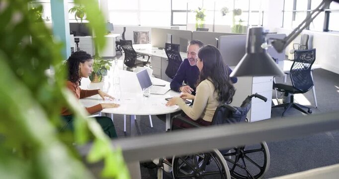 Diverse coworkers leaning in at meeting table after chart explanation and examining data on tablet