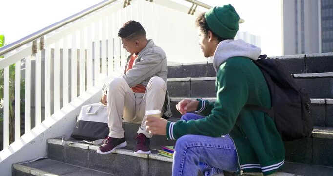 Reacting to gesture, diverse male friends on staircase pulling tablet and laughing at content