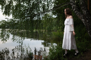 Elegance by the Lake: Woman in White Off-Shoulder Dress Among Birch Trees