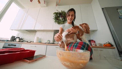 Woman enthusiastically mixes batter while spaniel rests on her lap