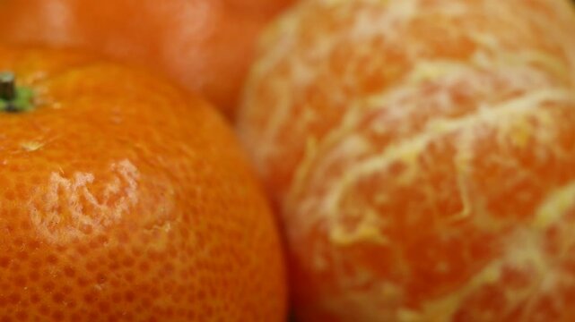 Detailed macro shot of several bright, juicy mandarin oranges ready to be peeled.