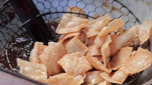 Deep Frying Wonton Skins or Pangsit Cracker Snacks in Hot Boiling Oil for Crispy Texture