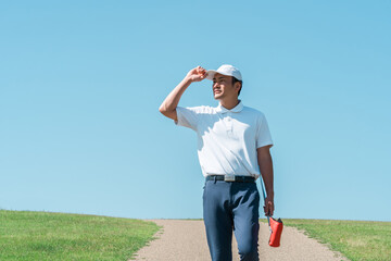 A man walking on a golf course with a putter and golf club
