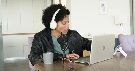 African American man at home aligning microphone for podcast typing on laptop checking smartwatch - Powered by Adobe