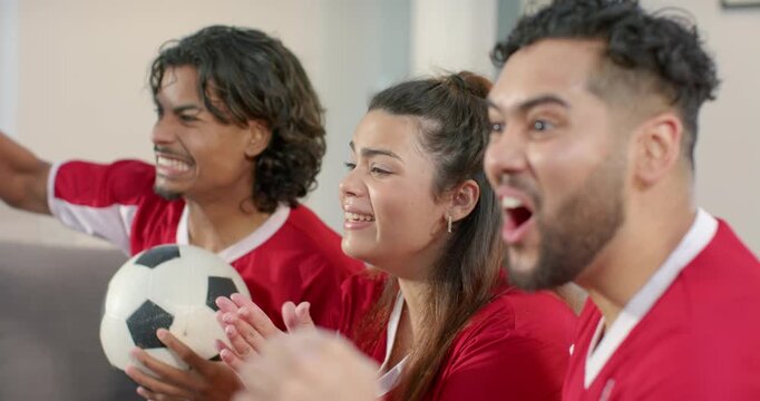Game intensifying Diverse friends in jerseys gripping ball clapping popcorn cheering in living room