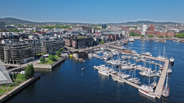4K Drone Aerial of Tjuvholmen Marina and Waterfront, Oslo, Norway. Boats docked and tourists walking the marina at Tjuvholmen Marina.