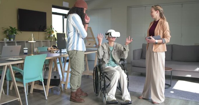 Diverse coworkers guiding wheelchair participant with VR controls, cheering with high-five