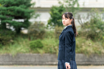 Junior high school, high school, and elementary school students in uniform standing in front of the school building
