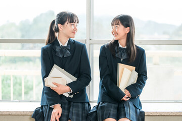 学校の教室で会話する小学生,中学生の女子生徒
