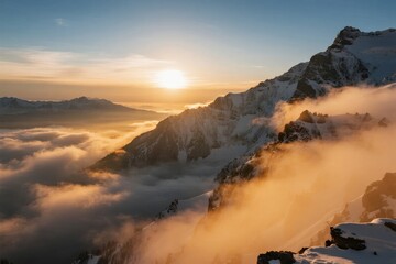 Sunrise over snow-covered mountain peaks with clouds below