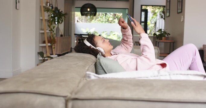 Hands are holding phone above face as clip starts, tapping then raising wrists on sofa scrolling