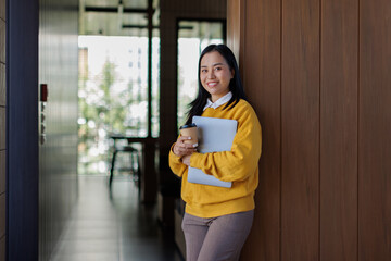 A woman in business in office confidently with a laptop in hand, smiling, and standing at office business growth finance report.