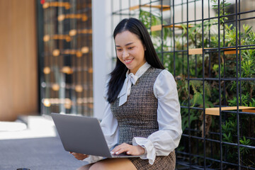 Profile portrait of young asian woman with laptop, girl student at outside and types on laptop computer.