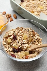 Making granola. Oat flakes, dried fruits, almond nuts and honey on grey textured table, closeup