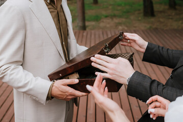 Fototapeta premium Businesspeople examining the contents of an open vintage briefcase during an outdoor meeting, symbolizing negotiation, deal-making, cooperation, and professional collaboration.