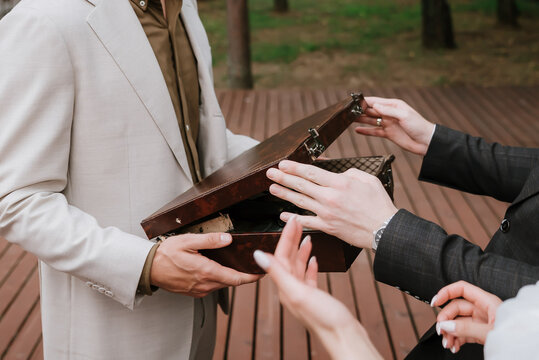 Businesspeople examining the contents of an open vintage briefcase during an outdoor meeting, symbolizing negotiation, deal-making, cooperation, and professional collaboration. - Powered by Adobe