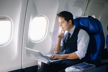 Businessman working on a laptop with documents during a first-class flight. Perfect for themes of productivity, corporate travel, and global business success.