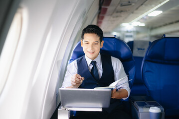 Businessman working on a laptop with documents during a first-class flight. Perfect for themes of productivity, corporate travel, and global business success.