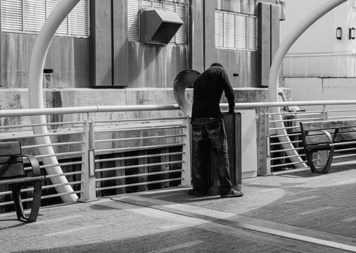 Homeless man on the bridge going through rubbish bin, looking for food