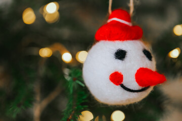 Christmas tree snowman decoration on a spruce branch with garlands. Christmas and New Years decor. Beautiful Christmas holiday background.Close-up of Snowman Ornament on Christmas Tree.
