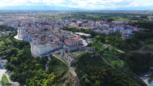 Coastal Ortona from sky: Adriatic waters, gentle waves, port marina, cliffside castle and charming historic seaside town.