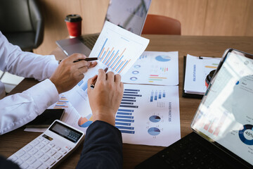 Business team analyzing financial charts and using a calculator during a meeting.