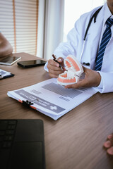Dental professionals discussing treatment plans with a tooth model and medical documents during a meeting.