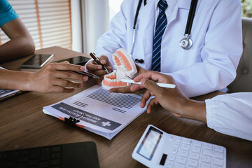 Dental professionals discussing treatment plans with a tooth model and medical documents during a meeting.