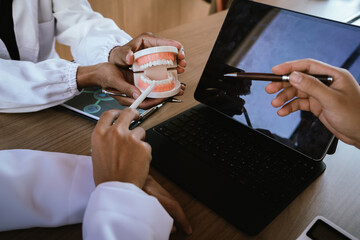 Dental professionals discussing treatment plans with a tooth model and medical documents during a meeting.