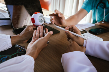 Doctor explaining eye anatomy using a detailed eyeball model during a medical consultation.