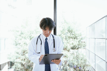 Doctor using a digital tablet to review medical information in a bright clinical environment.