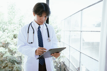 Doctor using a digital tablet to review medical information in a bright clinical environment.