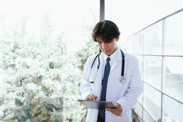 Doctor using a digital tablet to review medical information in a bright clinical environment.