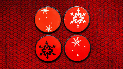 Close-up of four coasters arranged in a square on a red fabric texture.