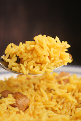 Eating rice dish on a spoon above a large plate
