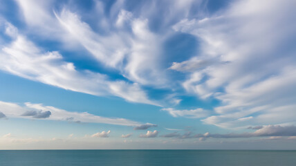 Obraz premium Wispy White Clouds Drifting Across a Blue Sky Over the Ocean cirrus