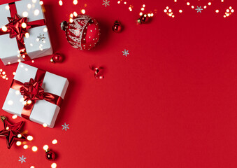 Christmas gifts with red glitter decorations on red background with bokeh. Merry Christmas and Happy New Year greeting card. Xmas and Winter holidays. Christmas banner, top view