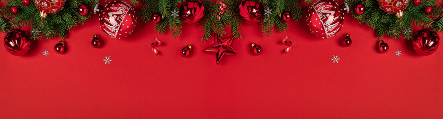 Merry Christmas and Happy New Year greeting card. Christmas tree branches with red glitter decorations on red background with bokeh. Xmas and Winter holidays. Christmas background, top view