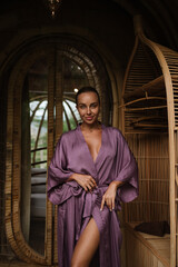 A woman in a purple robe poses inside a bamboo eco villa, surrounded by warm tones and natural textures