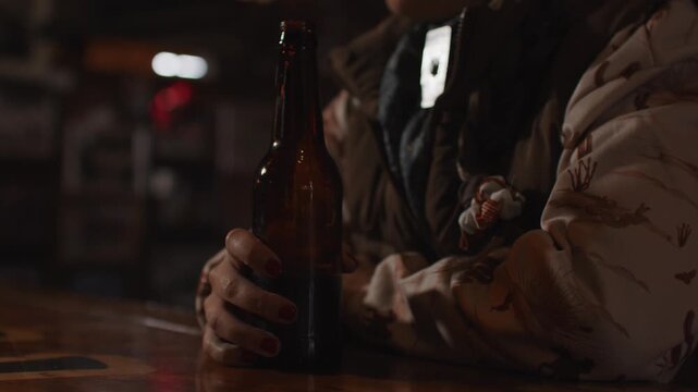 Close Up of Woman Wearing Cowboy Hat Holding Beer Bottle and Drinking Beer While Sitting at Bar Inside of Old Rustic Saloon
