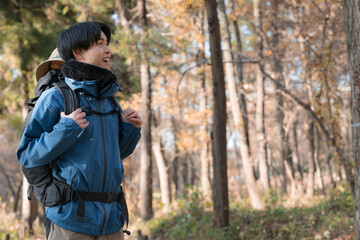 秋の紅葉の山を登山をする若い男性