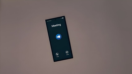 A smartphone screen displays a video meeting interface on a brown background, symbolizing modern remote communication and collaboration in a professional setting.