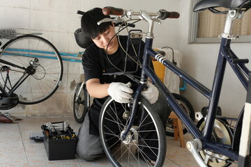 Authentic young tomboy repairing a flat bicycle tire in a garage. Independent female mechanic fixing a bike wheel with tools. DIY maintenance and empowerment concept.