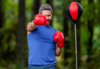 Strong athlete man boxer. Boxer in sportswear. Exercising and punching. Sportsman practicing boxing. Sportsman boxing punching bag outdoor. Sport man boxing punching bag. Bag target practice